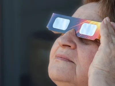 Dona major observa l’eclipsi solar amb ulleres de protecció