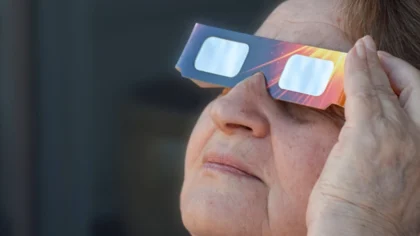 Dona major observa l’eclipsi solar amb ulleres de protecció