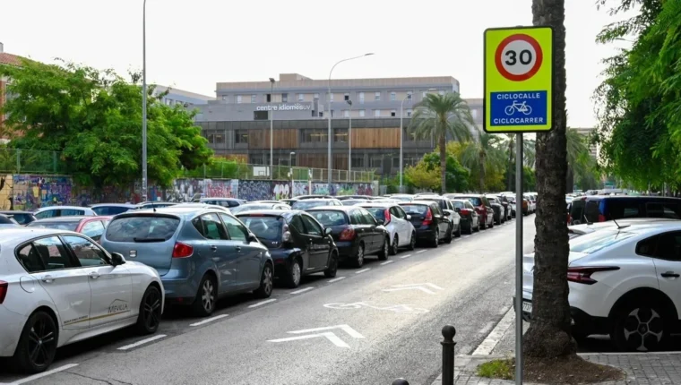 Carrer de València amb senyalització ciclista i vehicles estacionats.