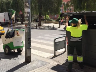 Operària del servici municipal de neteja obrint un contenidor al carrer a València