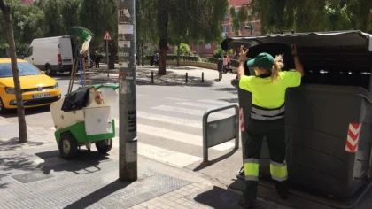 Operària del servici municipal de neteja obrint un contenidor al carrer a València