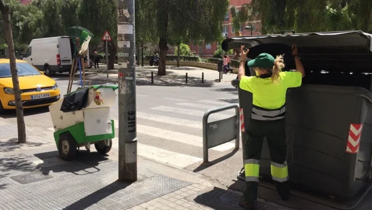 Operària del servici municipal de neteja obrint un contenidor al carrer a València